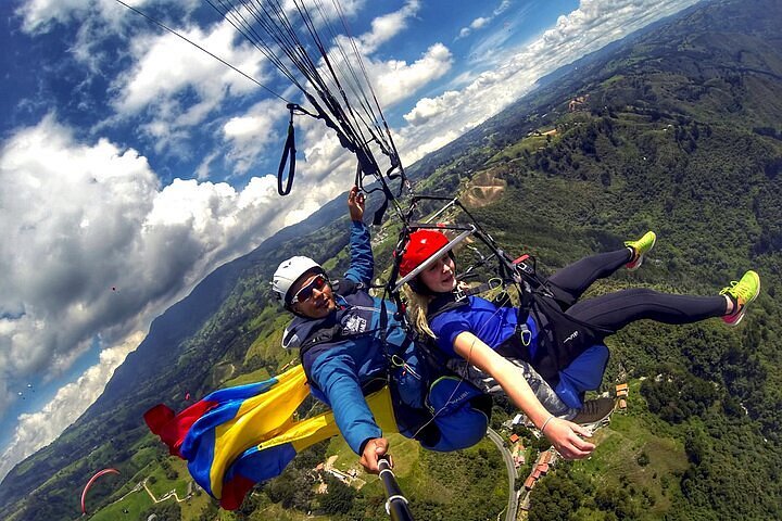 Parapente sobre las montañas de Antioquia con bandera de Colombia